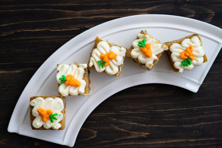 pieces of carrot cakes squares with walnuts and icing cream on a wooden background. selective focus.の写真素材