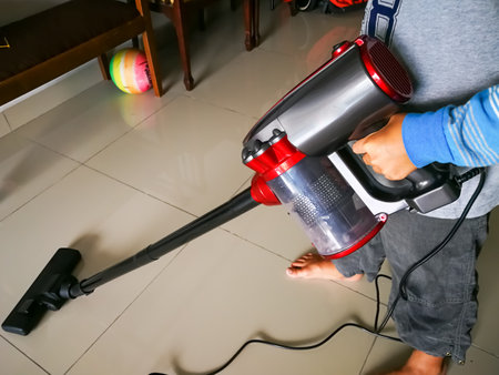 Kuala Lumpur, Malaysia - Nov 14, 2019: boy cleaning floor with hoover, Vaccum floor at home. Helping with chores.のeditorial素材