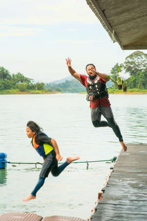 Motion of father and daughter jumping into the lake from the deck.