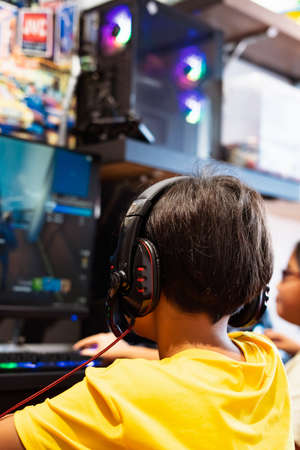 Wearing headphone, A gamer or a streamer boy at home in a room playing with friends on the networks in video games.の写真素材