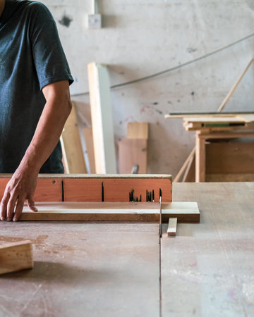A man cuts wood on a circular saw in a carpenter workshop.の写真素材
