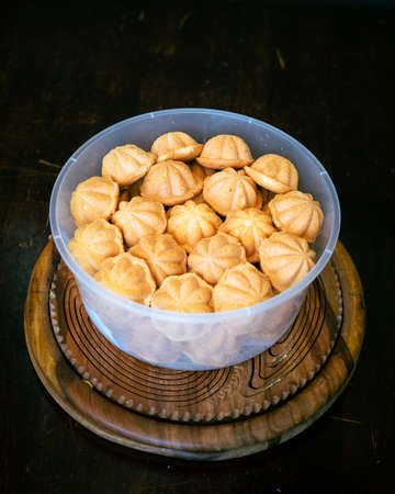 Kuih Bahulu, baulu or bolu in a container. Sponge cake baked in special aluminium moulds is the...