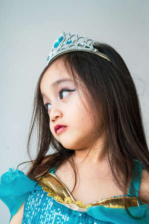 Portrait of a child girl dressed in arabian princess costume against white background. Natural light, selective focus.の写真素材