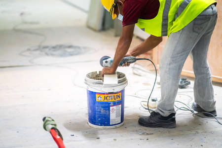 Kuala Lumpur, Malaysia - Jan 22, 2021: Worker using grinder for cutting tiles porcelain stoneware work trimming tiles. view of construction worker in construction siteのeditorial素材