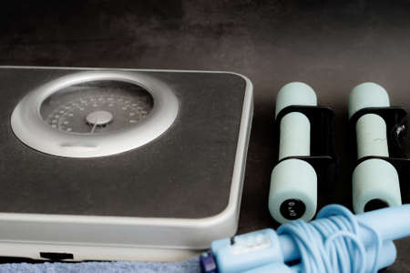 old weight scale, pair of weights dumbbells with skipping rope on dark background.の写真素材