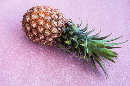 single whole pineapple on a pink gilttery background.の写真素材