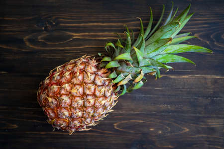 single whole pineapple on a wooden background.
