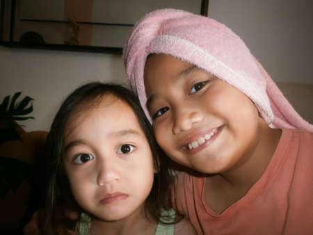 Self portrait of siblings girls. Older sister is wearing hair wrap towel and smiling.の写真素材