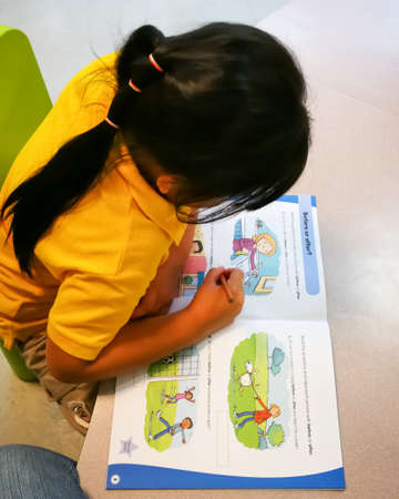 Selangor, Malaysia - January 2018: Top view of doing a workbook by a little girl.のeditorial素材