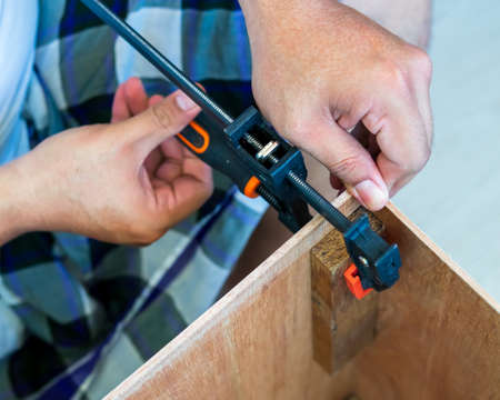 The carpenter uses the f-clamp to assemble the wooden box.