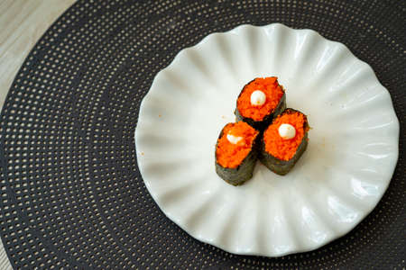 Salmon eggs or Ikura in Japanese style sushi fresh from raw salmond fish served on a white plate on dark background.の写真素材