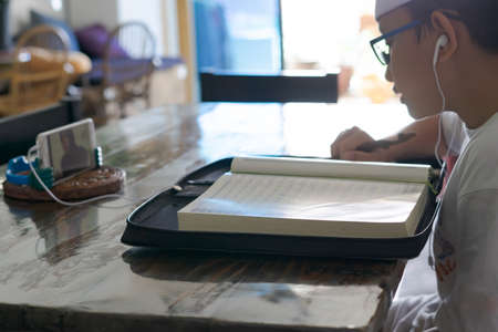 Kuala Lumpur, Malaysia - April, 2021 Asian kid reading Al-Quran through video call using smartphone during education and learning from home.のeditorial素材