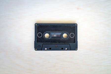 Old vintage audio cassette in black colour is on the wooden backgroundの写真素材
