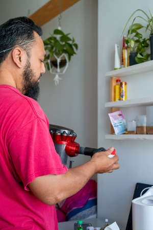 Asian bearded matured man is cleaning the house with vacuum cleaner.の写真素材