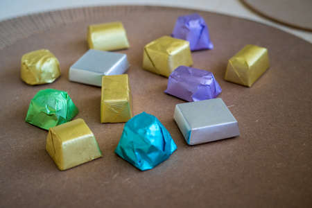 wrapped luxury chocolates in various colours for different flavours on a brown background.の写真素材
