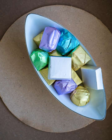 wrapped luxury chocolates in various colours for different flavours in a bowl on a brown background.の写真素材