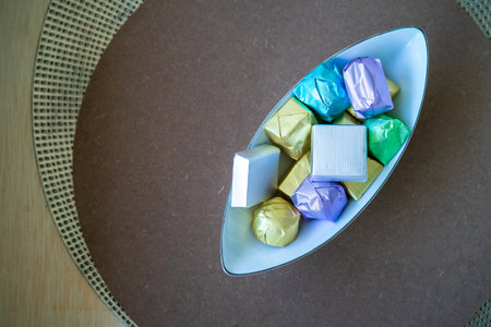 wrapped luxury chocolates in various colours for different flavours in a bowl on a brown background.の写真素材