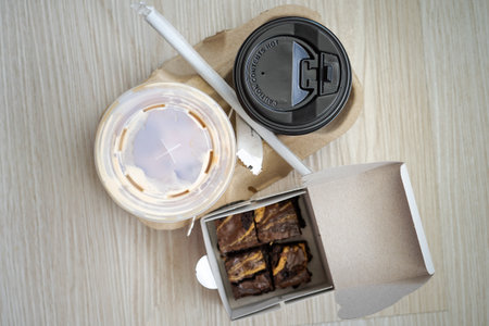 Hot and cold latte in a takeaway cups served with freshly baked brownies. Top view.の写真素材