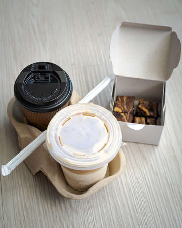 Hot and cold latte in a takeaway cups served with freshly baked brownies. High angle view.の写真素材