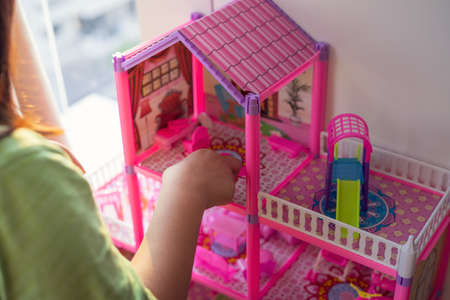 Pink doll house with a child playing with it.の写真素材