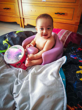Happy infant girl boy using training Bumbo seat to sit up at home.の写真素材