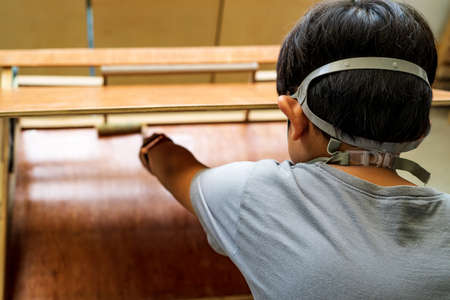 Young boy wearing half respiratory mask doing woodworking project. View from behind.の写真素材