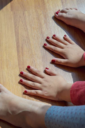 Hands and feets with henna in a bright sunlight on the floor. Drying henna at home.の写真素材