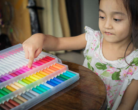 Little girl showing her colorful markers in transparent plastic packaging.の写真素材