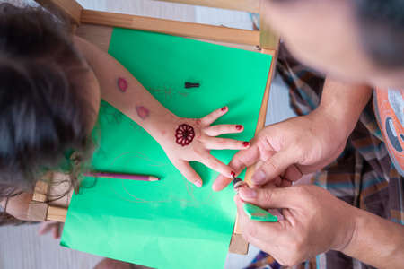 Painting henna ornaments on little girl's hand closeup.の写真素材