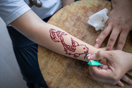 Painting henna ornaments on girl's hand closeup.の写真素材