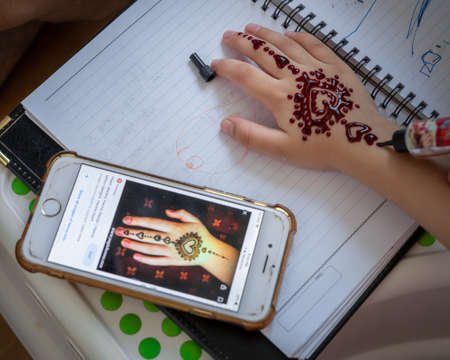 Kuala Lumpur, Malaysia - June 8, 2021 Painting Henna ornaments on little girl's hand closeup.のeditorial素材