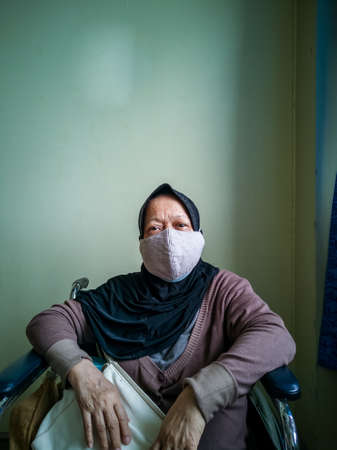 Portrait of a senior woman wearing hijab on wheelchair in a hospital.の写真素材