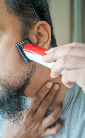 Man shaving beard with electric razor machine. Close-up.の写真素材