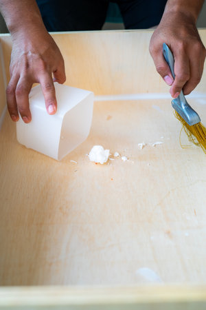 close up of male hand brooming wooden box with small whisk broom and recycled milk boxes as dustpanの写真素材