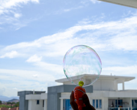 A large soap bubble is blowing from the blowerの写真素材