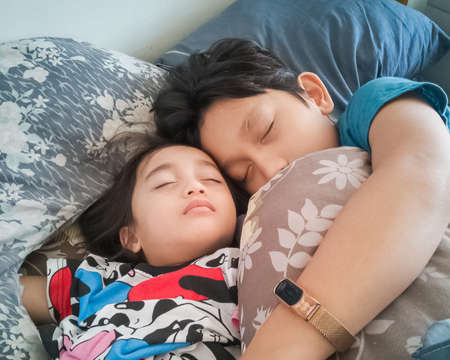Siblings sleeping on the bed.の写真素材
