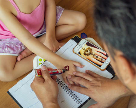 Kuala Lumpur, Malaysia - June 8, 2021 Painting Henna ornaments on little girl's hand closeup.のeditorial素材