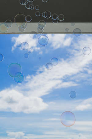 soap bubbles are floating with clouds and roof in the background.の写真素材
