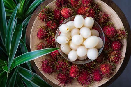 Rambutan, Malaysian sweet delicious fruits in bowl and bamboo plate in the balcony garden.の写真素材