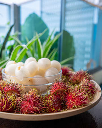 Rambutan, Malaysian sweet delicious fruits in bowl and bamboo plate in the balcony garden.の写真素材