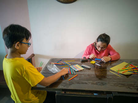 A young girl is constructing colorful plastic sticks with glue gun. fun with building geometric...