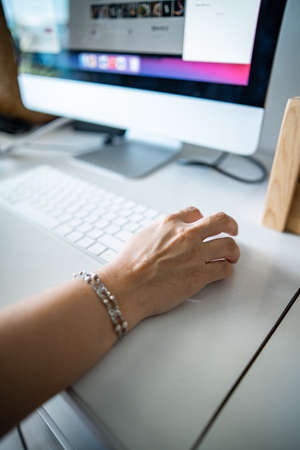 Closeup of woman's hand clicking mouse. Working at home.の写真素材