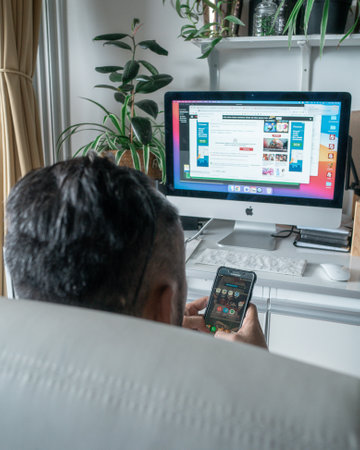 Kuala Lumpur, Malaysia - Aug 3, 2021 Working at home with computer. View of a man from behind using handphone.のeditorial素材