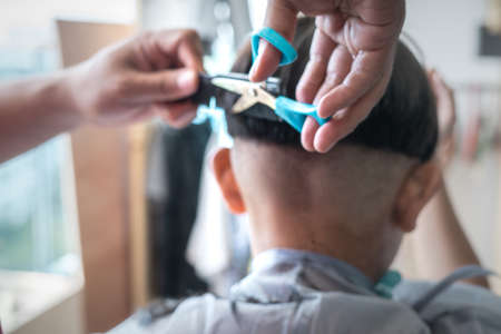 Blurry photo of Asian child getting haircut at home. View from behind.の写真素材