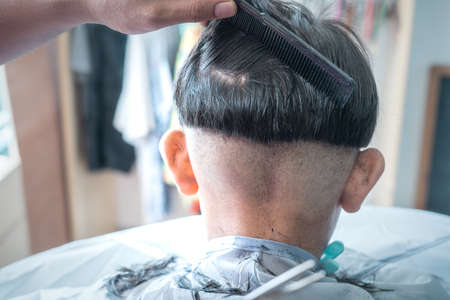 Asian child getting haircut at home from the father. View from behind.の写真素材