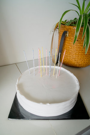 White cake with candles and blank background space on black cake board and wooden greenery background, birthday cake mockupの写真素材