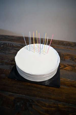 White cake with candles and blank background space on black cake board and wooden background, birthday cake mockupの写真素材
