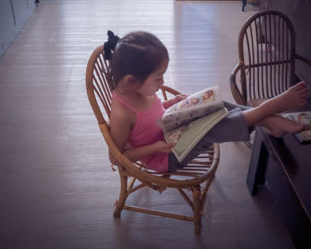 Little girl looking at a book at home.の写真素材