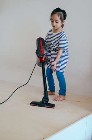 Cute little girl cleaning wooden floor with vacuum cleanerの写真素材