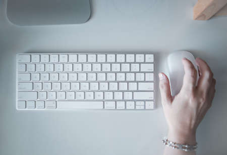 Top view of computer keyboard and hand using mouse over white office desk table.の写真素材